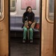 A woman sitting in a subway car with a face ams