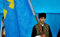 A young Crimean Tatar holds a flag.