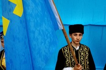 A young Crimean Tatar holds a flag.
