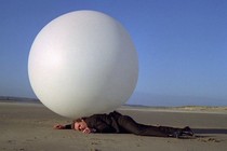 A man lays on the ground in front of a big white ball