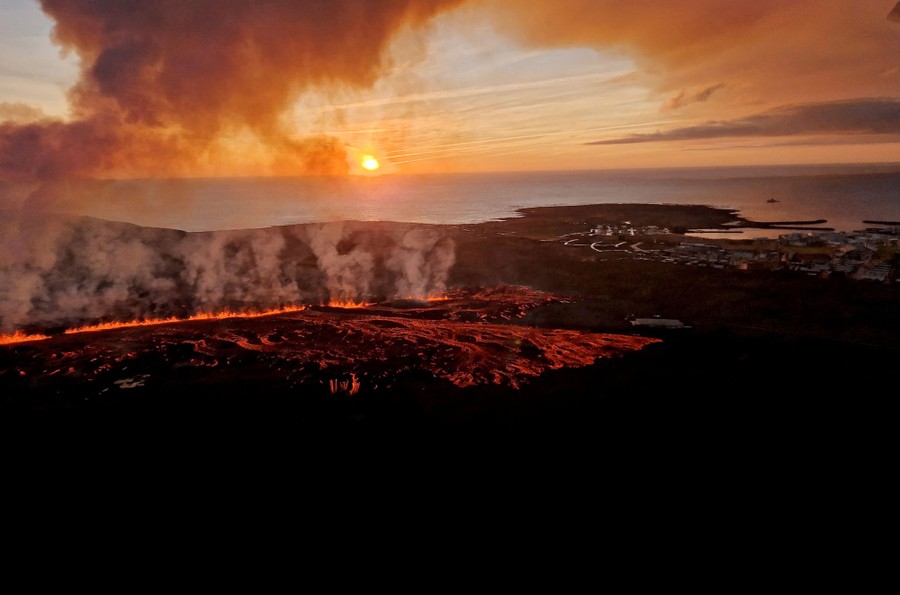 An aerial view of an active volcanic fissure near a town