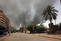 Picture of desolate urban street in Sudan, clouds of smoke in visible in the background