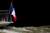 A boat flying a French flag navigates the Seine