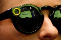 A woman wears Snapchat Spectacles on the floor of the New York Stock Exchange while waiting for Snap Inc. to list their IPO