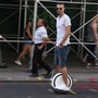 A person rides a one-wheeled hoverboard down a street.