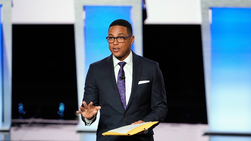 Don Lemon holding a yellow folder in front of three blue podiums