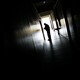 The silhouette of someone at the end of a dark hallway. 