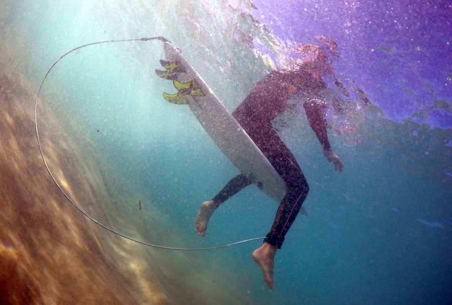 An underwater photo of a surfer sitting on his board