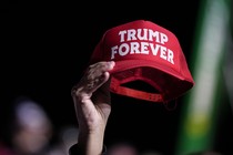A Trump supporter holds up a red baseball cap that reads: Trump Forever