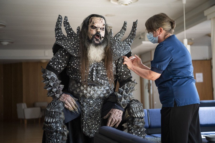 A heavy-metal singer in full costume gets a COVID-19-vaccination shot.