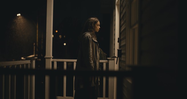 A still from Barbarian showing a woman on a porch in front of a door