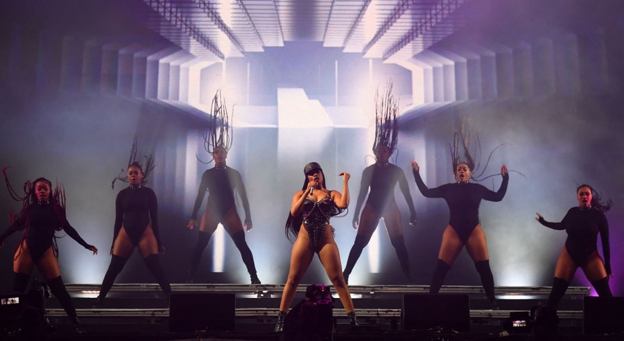 A singer and six backup dancers perform on a stage.