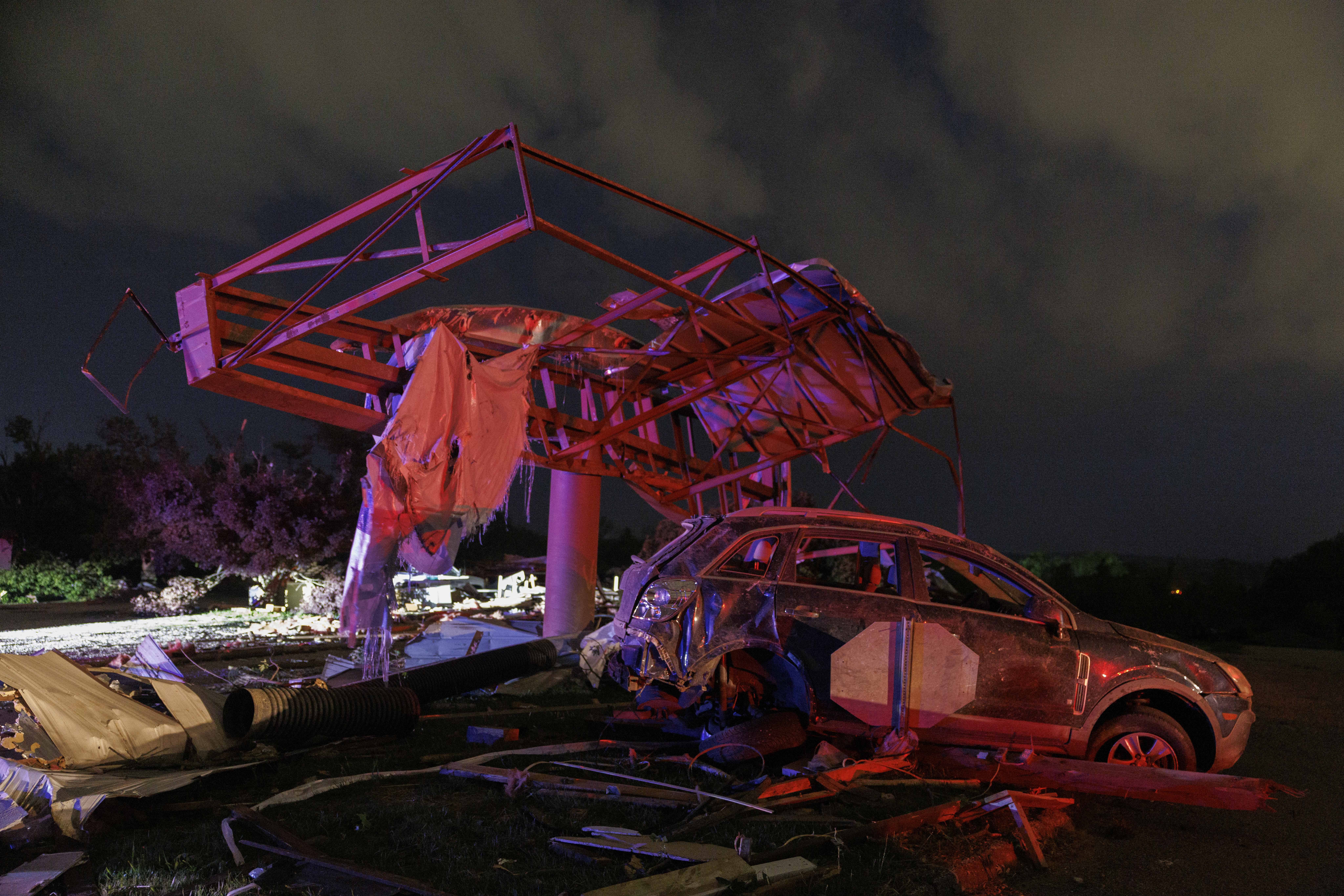 A billboard is seen twisted and a car mangled after a storm.