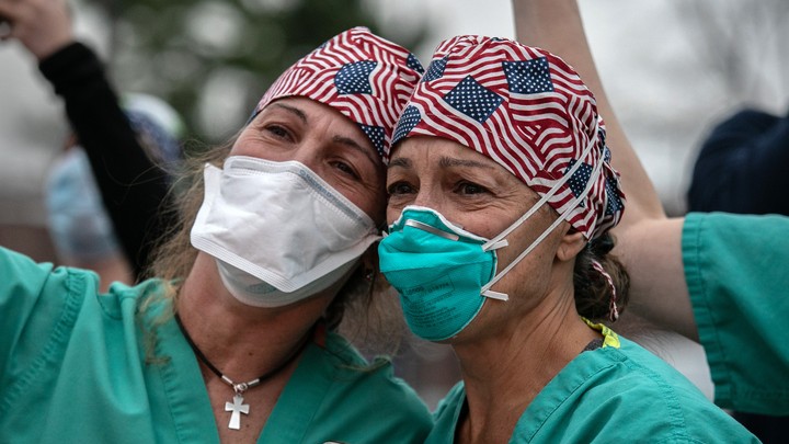 Healthcare workers wearing face masks and bandanas with American flags printed.