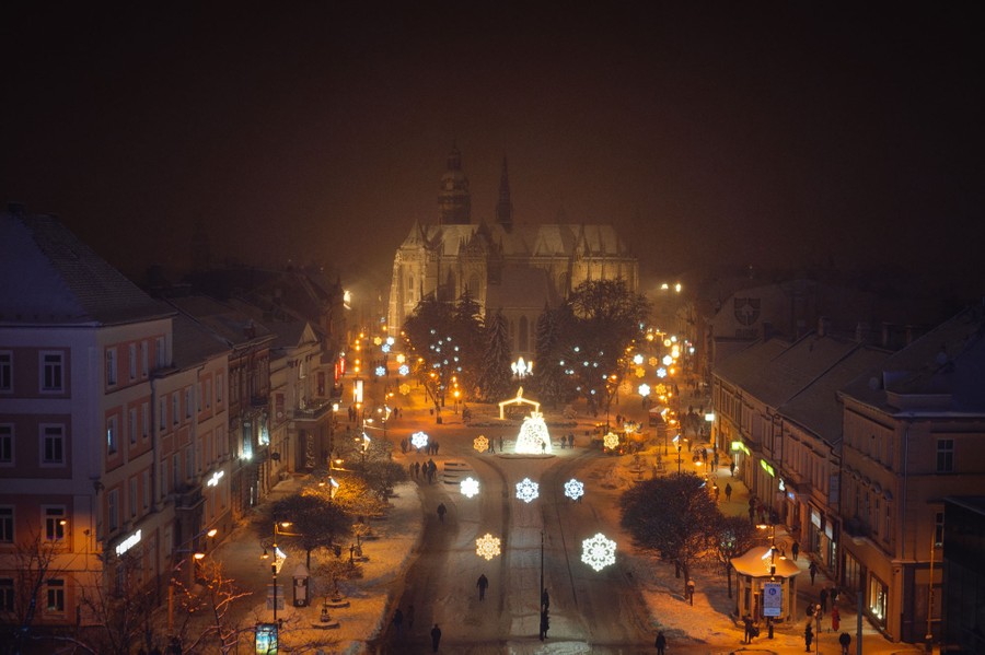 A nighttime view of a European city street decorated with many bright ornaments.