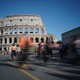 People bike past the remains of the ancient Colosseum in Rome