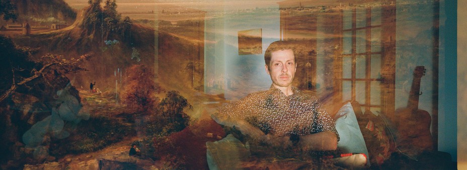 تصویری با نوردهی دوگانه، یکی از مردی که در اتاق نشیمن خود کنار گیتار نشسته با یک پوشش مبهم از یک نقاشی منظره قرن هفدهم