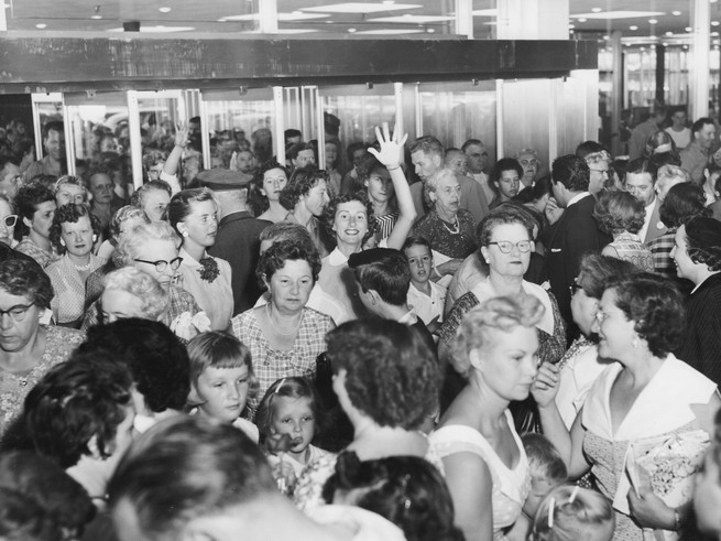 Black and white photo of crowd of people in mall