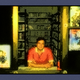 An illustration of a man in a red shirt sitting at a counter in a video store
