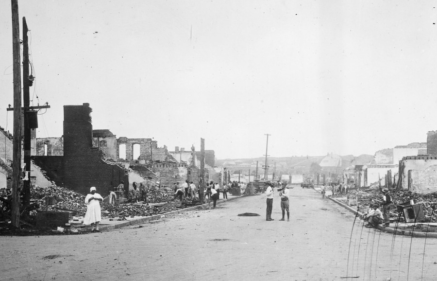 People dig through rubble of many destroyed buildings.