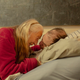photo of older woman with long hair sitting on edge of bed and hugging man lying propped up on pillows
