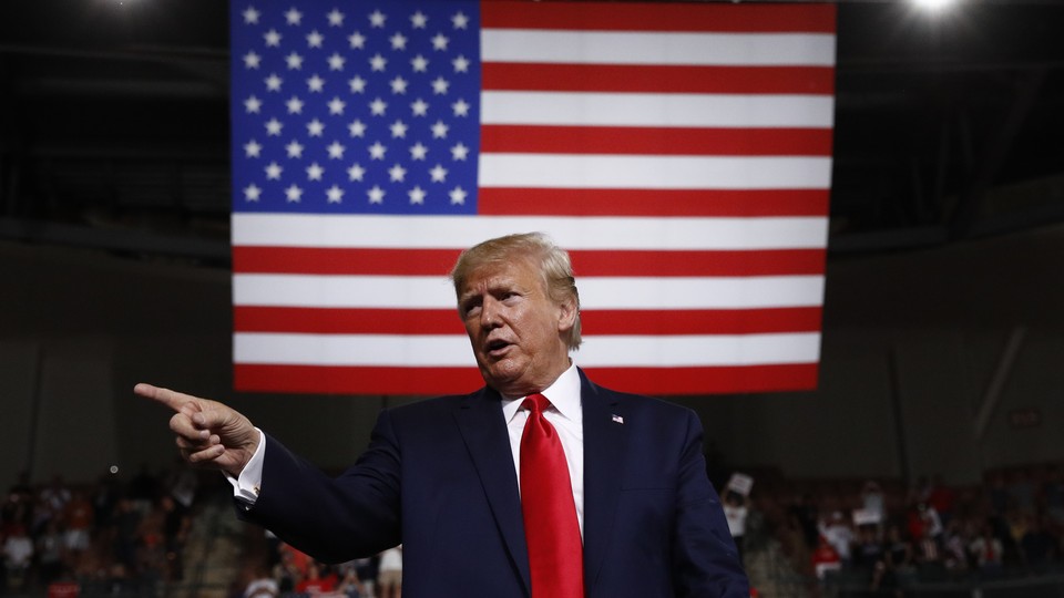 Trump standing in front of an American flag