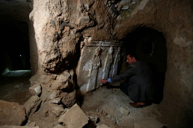 An archeologist displays artifacts in a tunnel under Jonah's Tomb (Suhaib Salem / Reuters)