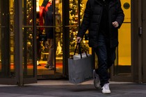 A shopper walks out of Neiman Marcus holding a shopping bag