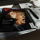 A magazine with a picture of President Donald Trump sits on top of other magazines and newspapers.
