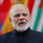 India's Prime Minister Narendra Modi looking at the camera in front of a row of flags.