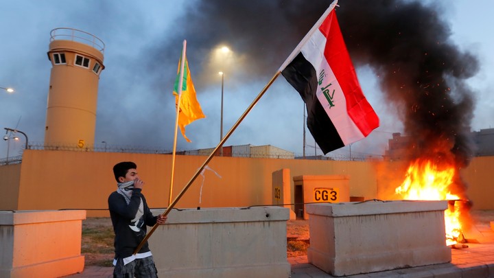 A protester holds an Iraqi flag outside the main gate of the U.S. embassy in Baghdad on December 31.