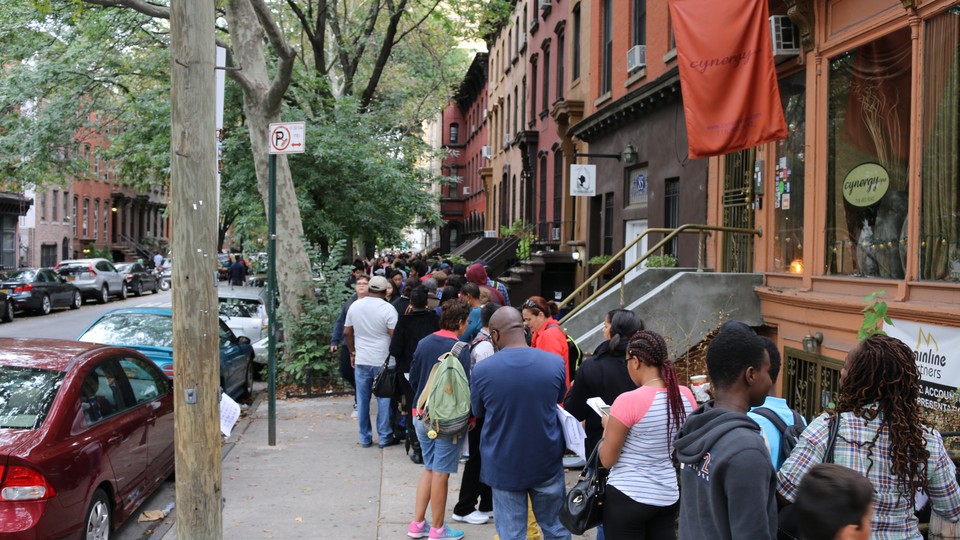 A long line of students and parents tumbles onto the New York City sidewalk.