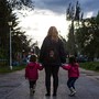 A mom with two children holding her hands.