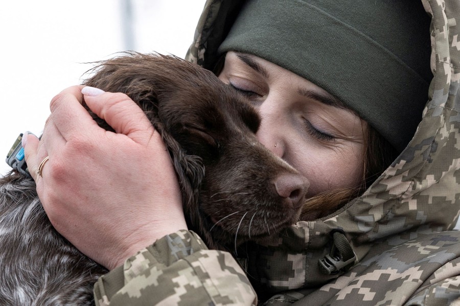 A soldier holds a dog close to her face.