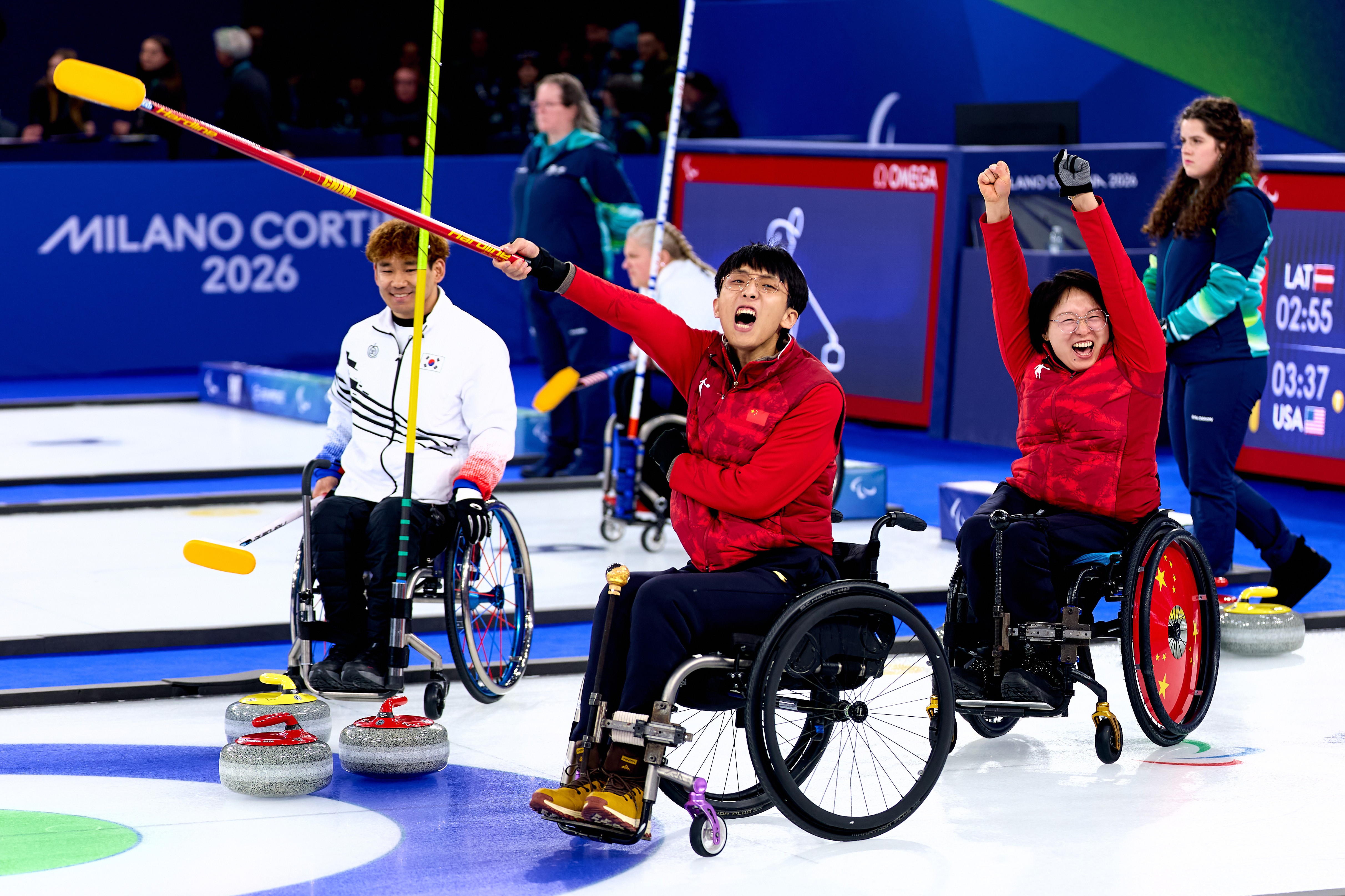 Two curling athletes in wheelchairs raise their arms in celebration after winning their gold-medal match.