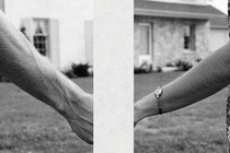 A man's arm and a woman's arm holding hands, with a big rectangular block through the center of the image