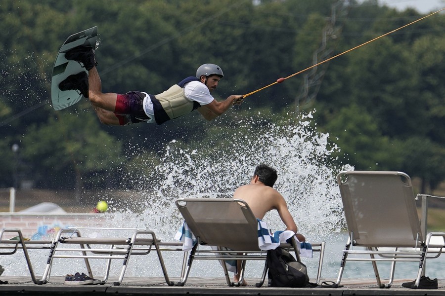 A person swings from a rope with a short surfboard strapped to his feet.