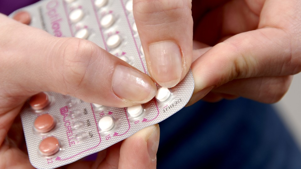 A person punches a birth-control pill out of a blister pack