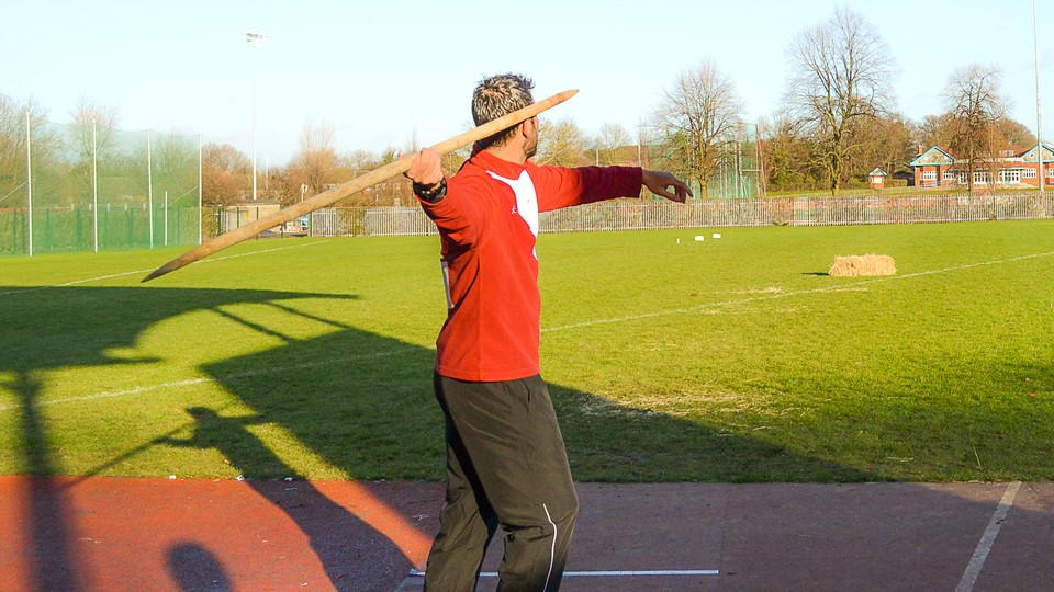 A javelin athlete throwing a replica Neanderthal spear
