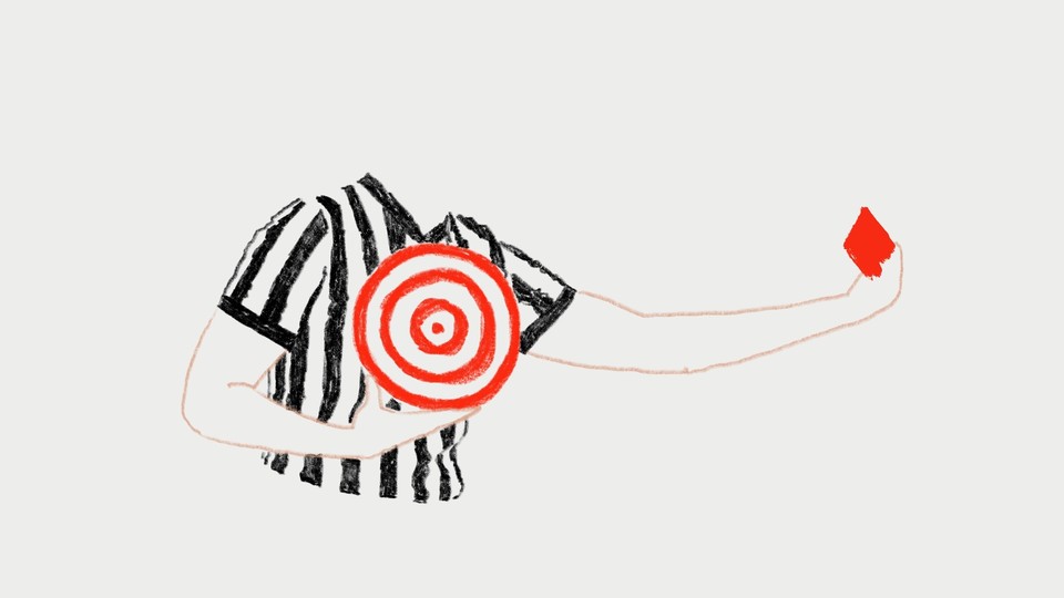 A faceless referee holding a red card out with one hand and a target on his chest with the other