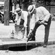 Two men pour liquor down a storm drain during the Prohibition era