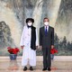 A masked Taliban official stands next to a masked Chinese official.