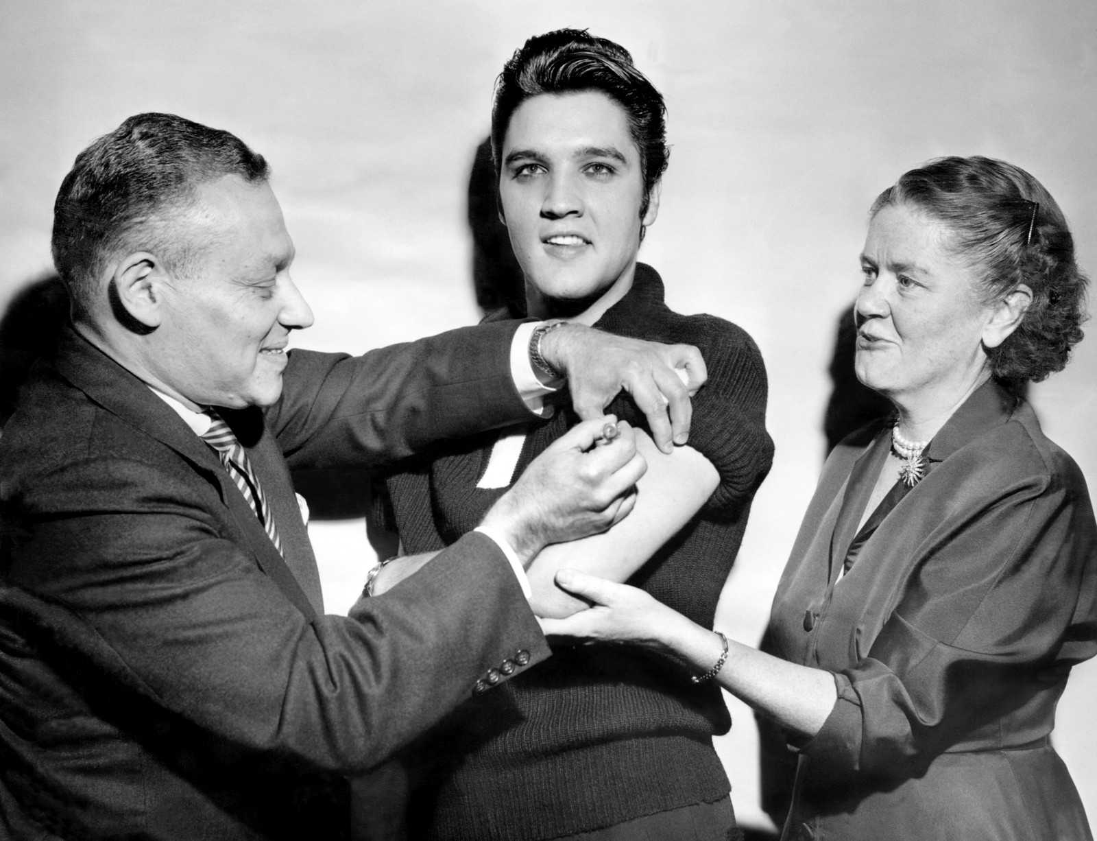 Elvis Presley smiles for cameras as he receives a polio vaccine shot.