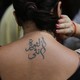 A person holds their hair up to reveal a tattoo in Arabic on their upper back.