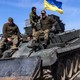 Soldiers flying a Ukrainian flag tow a damaged Russian tank from a field west of Kyiv in 2022.