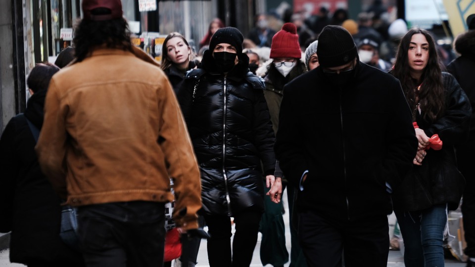 Masked and unmasked people, walking down a city street