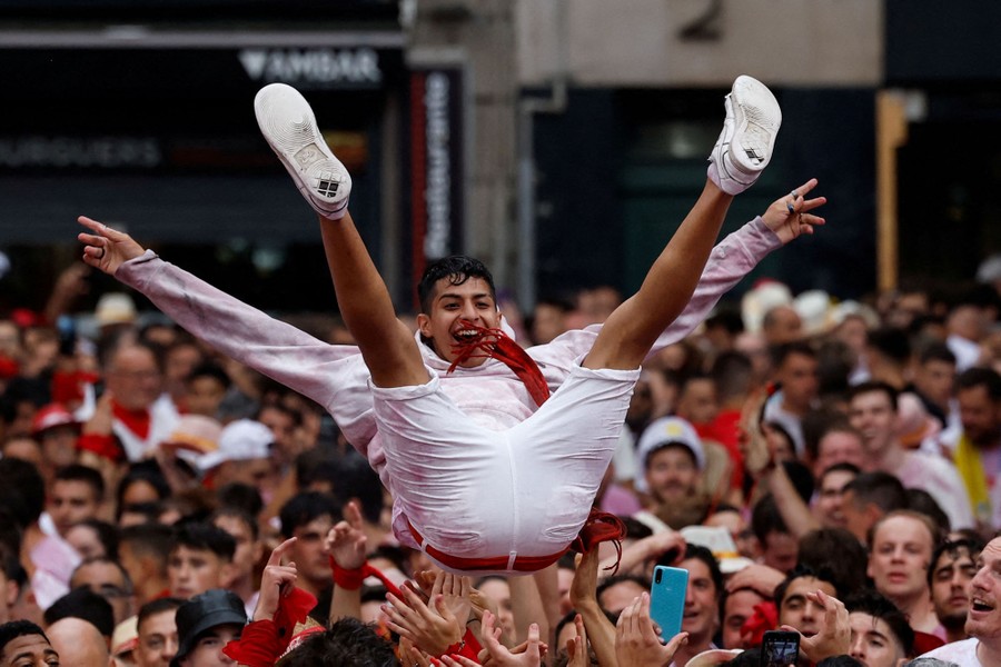 A person is tossed into the air by a large crowd in a plaza.