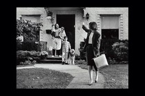Photo of a mother leaving for work, waving goodbye to her husband and children