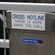 A metal box with a red button that says "push to call," and a placard reading "Crisis Hotline. There is hope make the call"