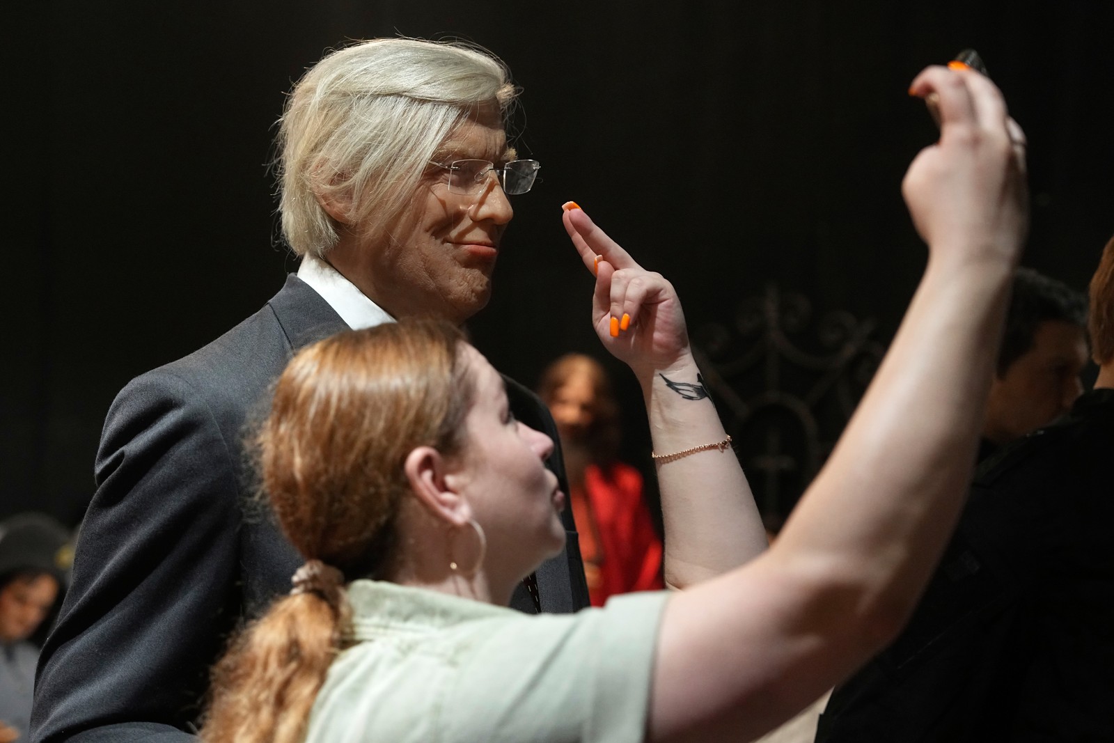 A woman takes a selfie with a wax sculpture purporting to resemble Donald Trump.